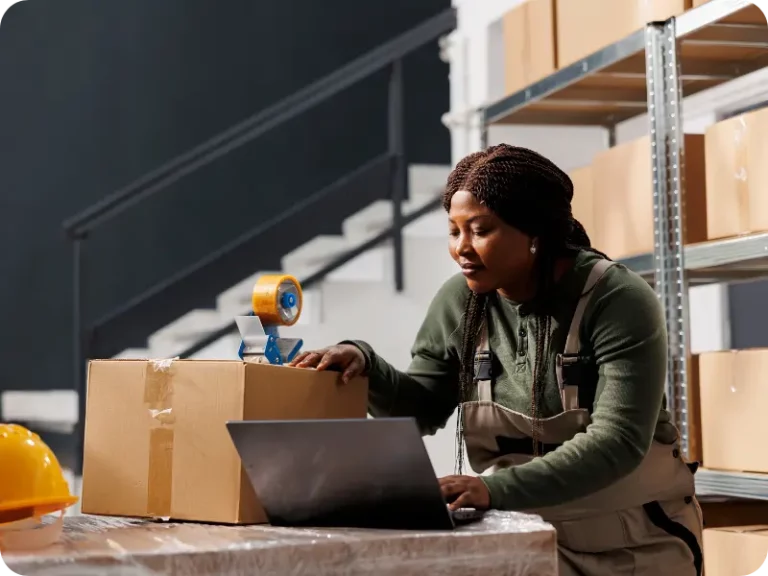 Une femme souriante dans un entrepôt et utilisant un WMS.